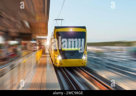 Straßenbahnfahrt in Bewegung verschwimmt an der Straße kommt mit Passagieren am Bahnhof an. Stockfoto