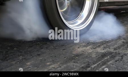 Ziehen Sie den brennenden Reifen des Rennwagens an der Startlinie auf der Rennstrecke Stockfoto