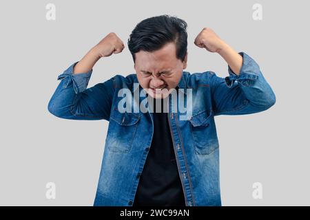 Junger asiatischer Mann mit deprimiertem Ausdruck mit Handflächen zum Kopf. Auf isoliertem Hintergrund Stockfoto