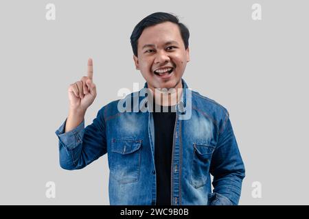 Junger asiatischer Mann, der die Hand auf den leeren Raum zeigt, auf isoliertem Hintergrund Stockfoto