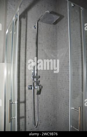 Eine Nahaufnahme eines luxuriösen Badezimmers mit quadratischer Duschschiene aus Edelstahl, Sprühdose in einem grauen, modernen Badezimmer. Stockfoto