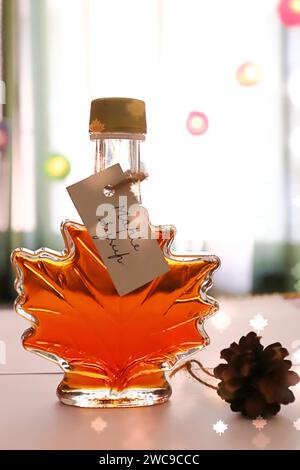 Ahornsirup in einer Ahornblattförmigen Flasche mit handgeschriebenem Etikett/Stillleben Stockfoto