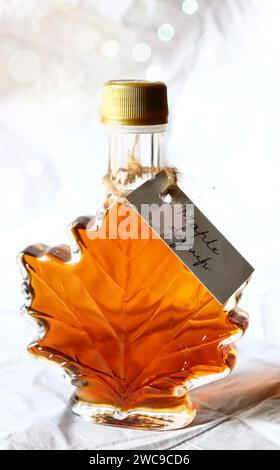 Ahornsirup in einer Ahornblattförmigen Flasche mit handgeschriebenem Etikett/Stillleben Stockfoto