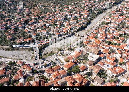 Leonidio, Arcadia, Peloponnes, Griechenland. Panoramablick auf die Landwirtschaftsstadt mit traditionellem Gebäude, trockenem Flussbett Dafnon, Brücke. Stockfoto