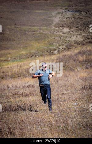 Sportlicher Mann steigt aktiv vom Berg ab, fühlt Adrenalin und Bewegungsfreiheit Stockfoto
