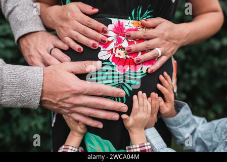 Kinderhände und Elternhände, die den schwangeren Bauch der Mutter halten Stockfoto