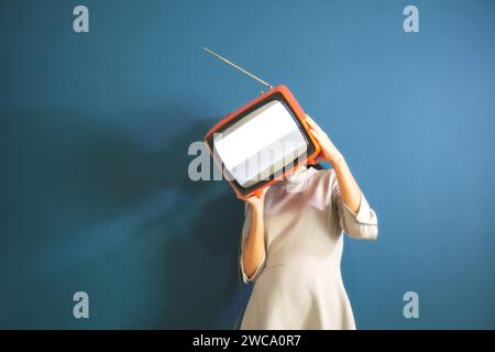Surreale Frau bedeckt ihr Gesicht mit einem Fernseher ohne Verbindung, abstraktes Konzept Stockfoto