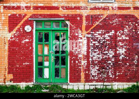 Alte grüne Holztür auf einem ruinösen Gebäude mit verwitterter Fassade Stockfoto