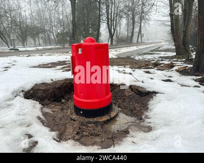 Roter Hydrant in der Nähe der Straße, schneebedeckter Winter, Bäume ohne Blätter. Stockfoto