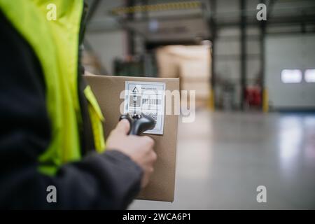 Lagerarbeiter scannt Barcode auf Karton. Empfangsmitarbeiter, der einen Scanner hält und die gelieferte Ware mit der Bestellung überprüft. Stockfoto