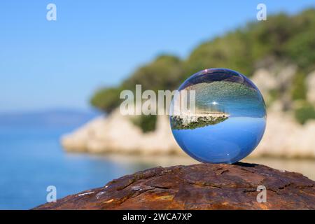 Glaskugel liegt auf einem rostigen Poller, sonniger Herbsttag in Cres (Kroatien) Stockfoto