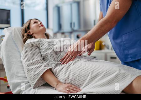 Arzt tastend den Bauch der Frau, mit Händen und gleichmäßigem Druck. Stockfoto