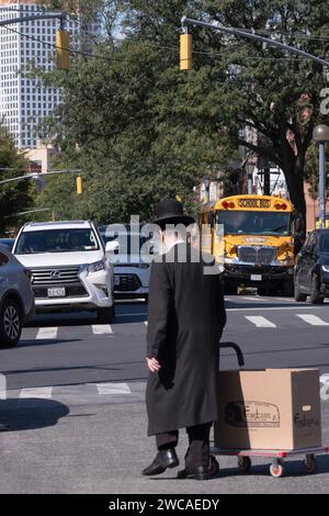 Ein älterer chassidischer jüdischer Mann überquert Lee Ave mit einer großen Schachtel Backwaren von Franczoz, einem koscheren Bäcker. In Williamsburg, Brooklyn, New York. Stockfoto