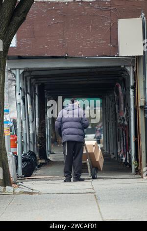 Ein anonymer orthodoxer jüdischer Arbeiter schiebt einen Handwagen an einer Baustelle in der Ross Street in Williamsburg, Brooklyn, vorbei Stockfoto