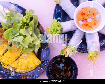 Zwei vietnamesische Gerichte, Banh xeo und goi cuon (Frühlingsrollen) mit Gewürzen in einem Restaurant in Thanh Hoa, Vietnam. Geringe Schärfentiefe mit dem spr Stockfoto