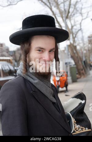 Posiertes Porträt eines lächelnden chassidischen Mannes mit langem gelocktem Peyus. An einem Wintertag Ende 2023 in Brooklyn, New York. Stockfoto