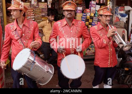 Drei uniformierten Mitglieder einer Band für Hochzeiten und andere Feierlichkeiten beschäftigt, ihre Trommeln und Trompeten spielen in einer Seitenstraße in Mumbai, Indien Stockfoto