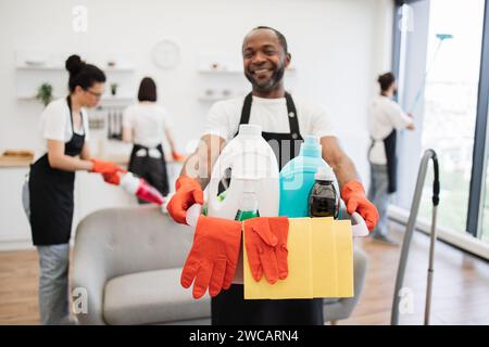 Konzentrieren Sie sich auf den Eimer mit Reinigungsmitteln in den Händen eines afrikanischen Reinigungsarbeiters. Stockfoto