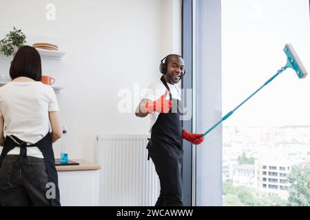 Afrikanische Fenster mit Mopp waschen, Musik in Kopfhörern hören und tanzen. Stockfoto