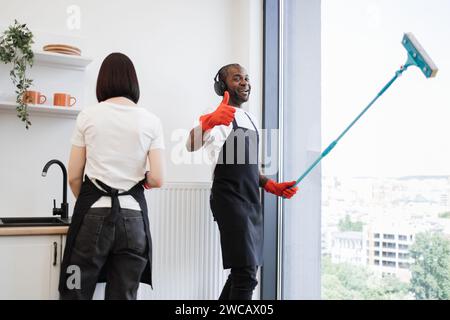 Afrikanische Fenster mit Mopp waschen, Musik in Kopfhörern hören und tanzen. Stockfoto