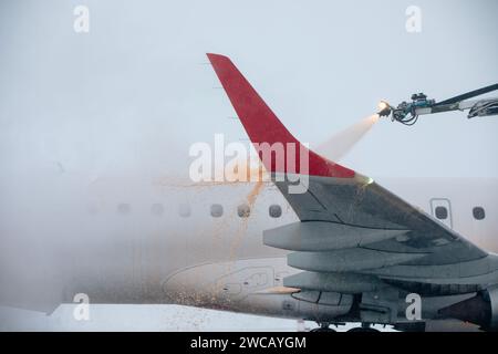 Enteisung des Flugzeugflügels vor dem Flug. Winter frostiger Tag und Bodenservice am Flughafen bei Schneefall. Stockfoto