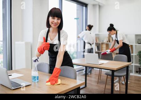Kaukasische Hausmeisterin auf schwarzem Schürzenputztisch mit Waschmittel Stockfoto