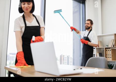 Kaukasischer Arbeiter in einer schwarzen Schürze, der Panoramafenster reinigt. Stockfoto