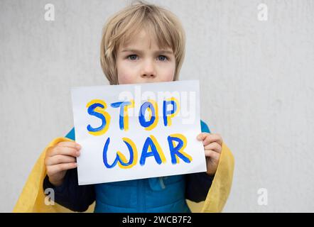 Ukrainischer Junge mit traurigem, ernsthaftem Blick, der gegen den Krieg in der Ukraine protestiert. Ein Poster mit den Worten Stop war in Blau und Gelb. Mi Stockfoto