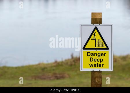 Danger Deep Water Schild auf einem Holzpfosten neben einem See Stockfoto