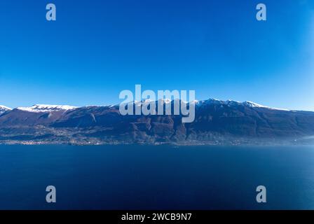 Blick von Tignale auf den Gardasee auf das Panorama der schneebedeckten Gipfel des Monte Baldo. Stockfoto