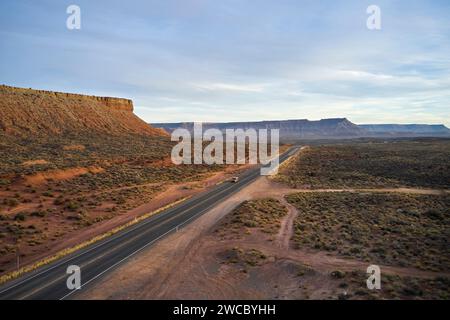 Mehrere Fahrzeuge fahren die Route 9 durch die Wüste von Utah. Es wird dunkel, und die nahe gelegenen Berge fangen die letzten Lichtstrahlen auf, wenn die Sonne untergeht. Stockfoto