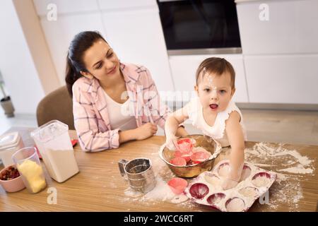 Mutter und kleines Mädchen bereiten den Teig in der Küche vor, backen Kekse. Glückliche gemeinsame Zeit Stockfoto