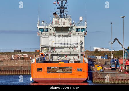 Das Versorgungsschiff mit der orangefarbenen Plattform liegt an sonnigen Tagen im Hafen. Stockfoto