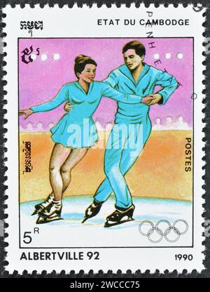 Von Kambodscha gedruckte Briefmarke, auf der Eiskunstlauf, die Olympische Winterspiele in Albertville um 1990 gezeigt wird. Stockfoto