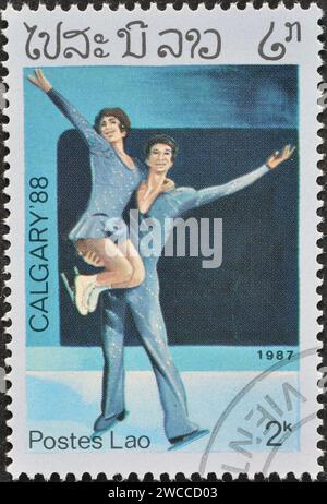 Laos - um 1989 : Briefmarke mit abgebrochenem Briefdruck von Laos, die Eiskunstlauf zeigt, Werbung für die Olympischen Winterspiele 1992 - Albertville, um 1989. Stockfoto