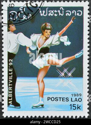 Laos - um 1989 : Briefmarke mit abgebrochenem Briefdruck von Laos, die Eiskunstlauf zeigt, Werbung für die Olympischen Winterspiele 1992 - Albertville, um 1989. Stockfoto