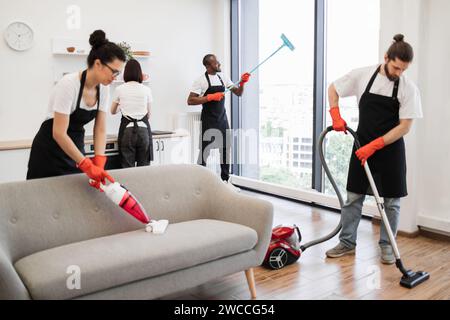 Team von Servicemitarbeitern, die Sofa, Teppich, Küchentisch und Panoramafenster reinigen. Stockfoto