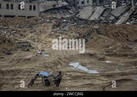 Gaza-Stadt, Palästinensische Gebiete. Januar 2024. Palästinensische Kinder retten nach hundert Tagen des Isarel-Hamas-Krieges einige Gegenstände aus dem zerstörten Viertel Scheich Radwan in Gaza-Stadt. Quelle: Omar Ishaq/dpa/Alamy Live News Stockfoto