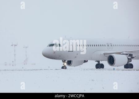 Verkehr am Flughafen bei Schneefall. Passagierflugzeug, das an frostigem Wintertag zum Start auf die Start- und Landebahn fährt. Stockfoto