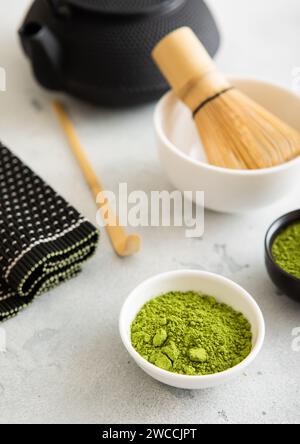 Matcha Grünteepulver mit Bambuslöffel und Schneebesen in einer Keramikschale mit Wasserkocher auf weiß. Stockfoto