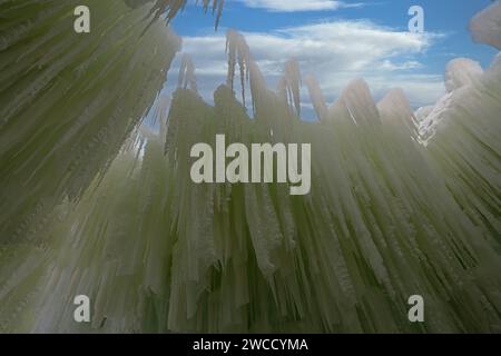 Blick auf eine hoch aufragende Eiszapfwand, die von hinten von grünen Lichtern beleuchtet wird, in Ice Castles am Genfer See, Wisconsin, USA Stockfoto