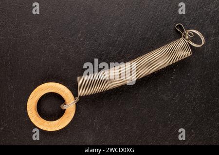 Eine Metallfeder mit Holzring auf Schieferstein, Makro, Draufsicht. Stockfoto