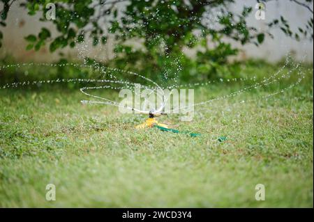 Sprühen Sie mit Wasser Rasenrasen auf unscharfem Hintergrund Stockfoto