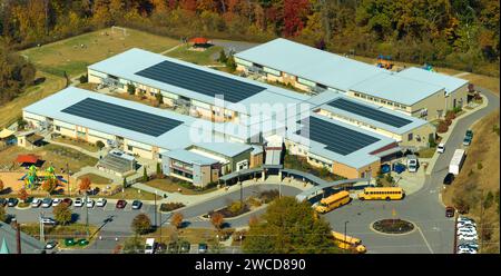 Luftaufnahme des amerikanischen Schulgebäudes auf dem Dach mit Photovoltaik-Solarpaneelen für die Stromerzeugung Stockfoto