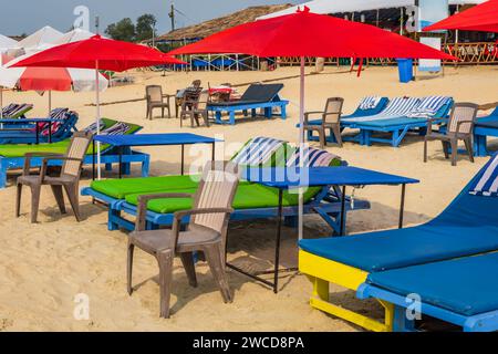 Bunte hölzerne Sonnenschirme und Liegestühle am Sandstrand des Meeres Stockfoto