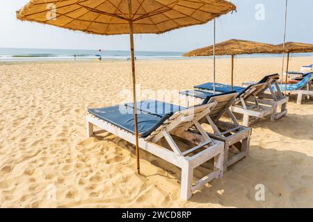 Bunte hölzerne Sonnenschirme und Liegestühle am Sandstrand des Meeres Stockfoto