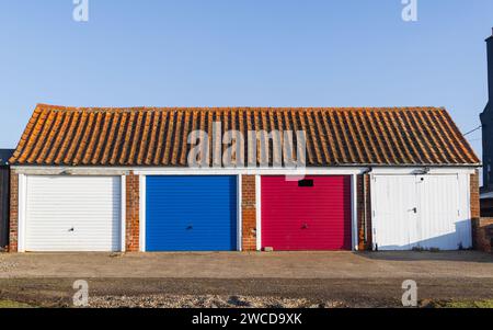 Block mit vier Garagen mit farbigen Türen und einem gekachelten Dach. Suffolk. UK Stockfoto