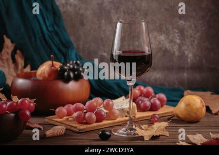 Herbstpicknick mit Wein- und Käseplatte, Früchten und trockenen Blättern Stockfoto