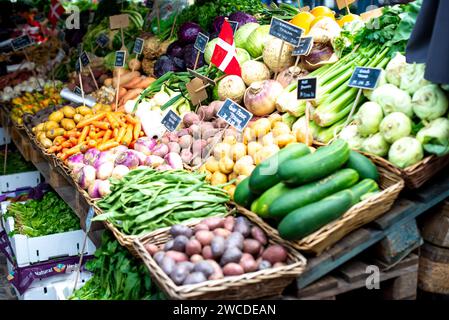 Ein lebhaftes Sortiment an frischem Obst und Gemüse, ordentlich in rustikalen Körben angeordnet, wird auf einem geschäftigen Markt vorgeführt Stockfoto