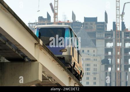 Stadtzugwagen auf hoher Eisenbahn über Straßenverkehr zwischen Wolkenkratzern im modernen amerikanischen Megapolis. Stadtverkehr in der Innenstadt Stockfoto